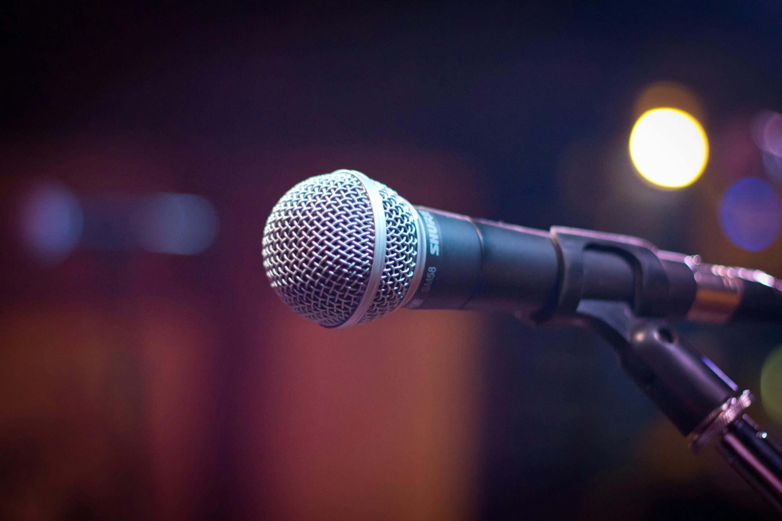 Dynamic microphone on stand with blurred stage lights in background.