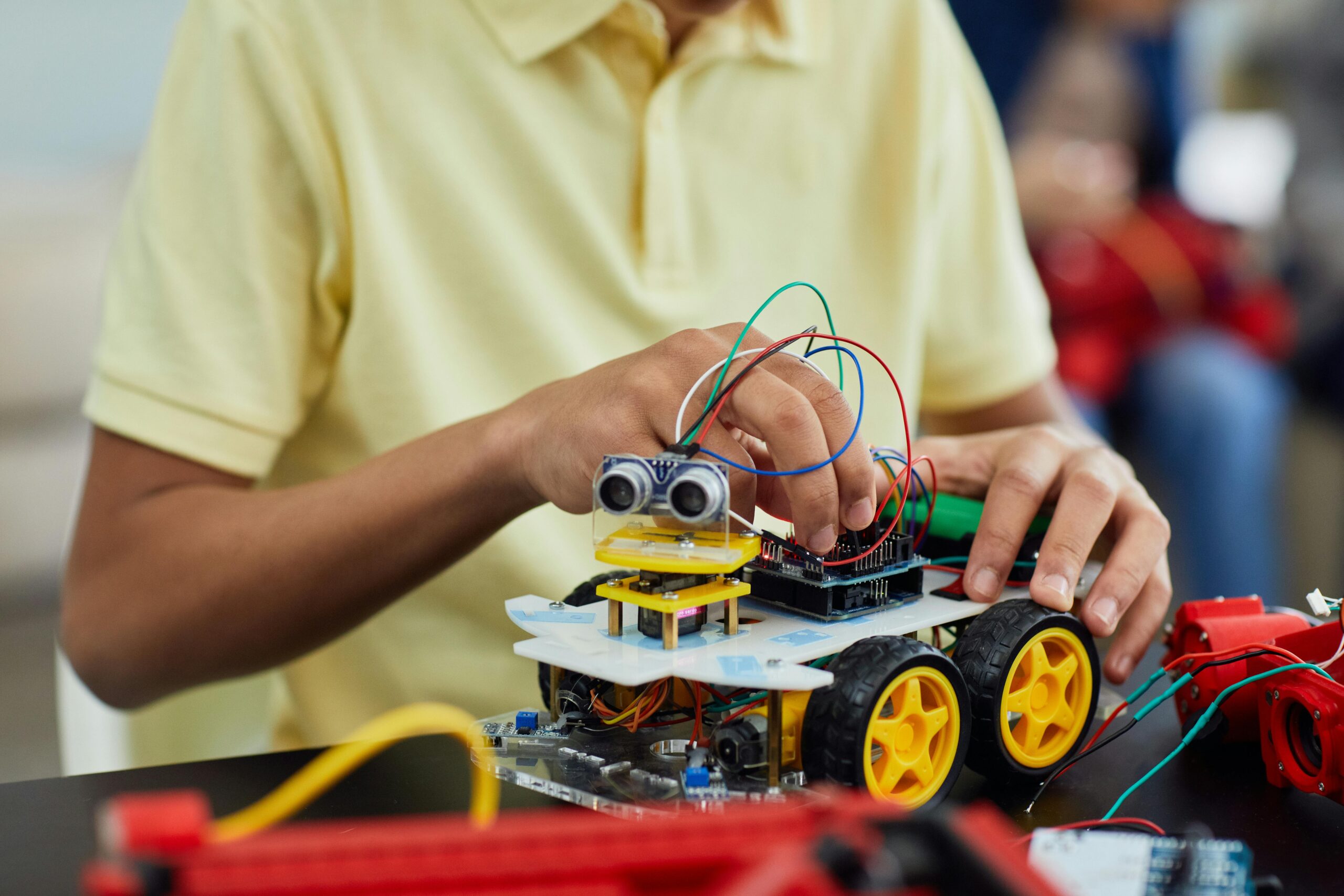 A child engaging in a STEM activity by assembling a robotic toy car featuring electronics and wiring.